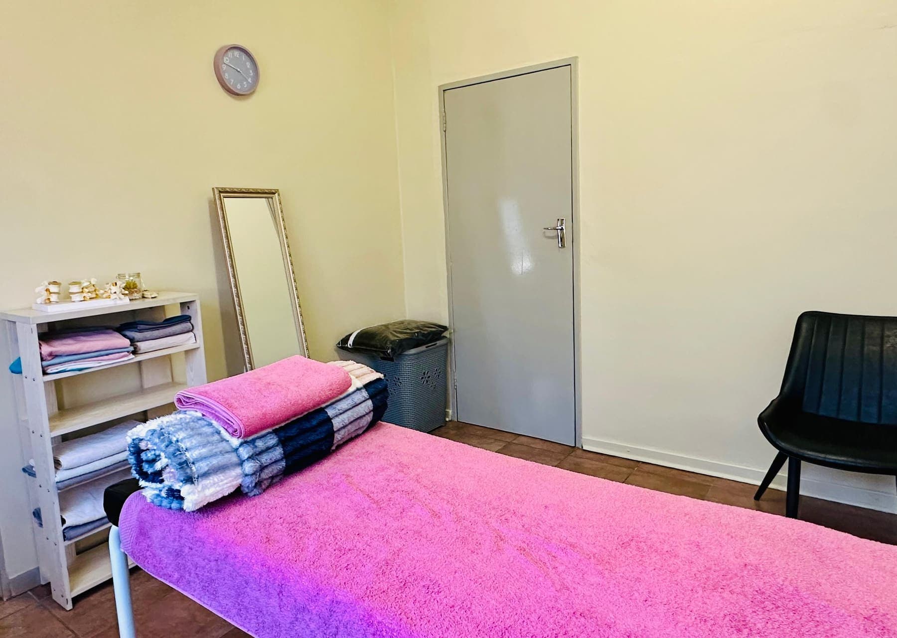 A treatment room at the African Mall clinic with a made-up plinth, folded linen and a full-length mirror.