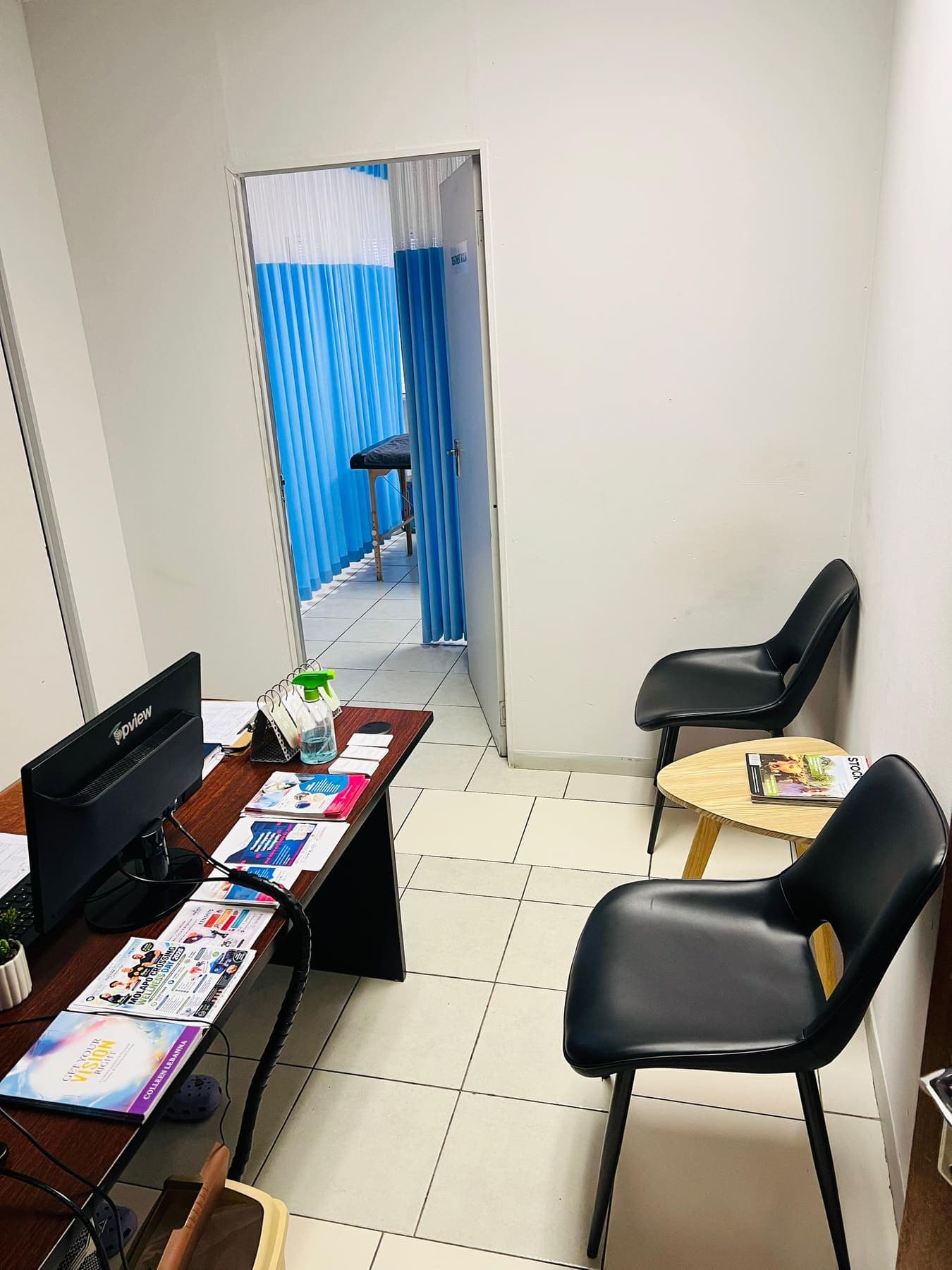 The Molapo Crossing reception desk with waiting chairs and a view through to the blue curtained treatment bay.