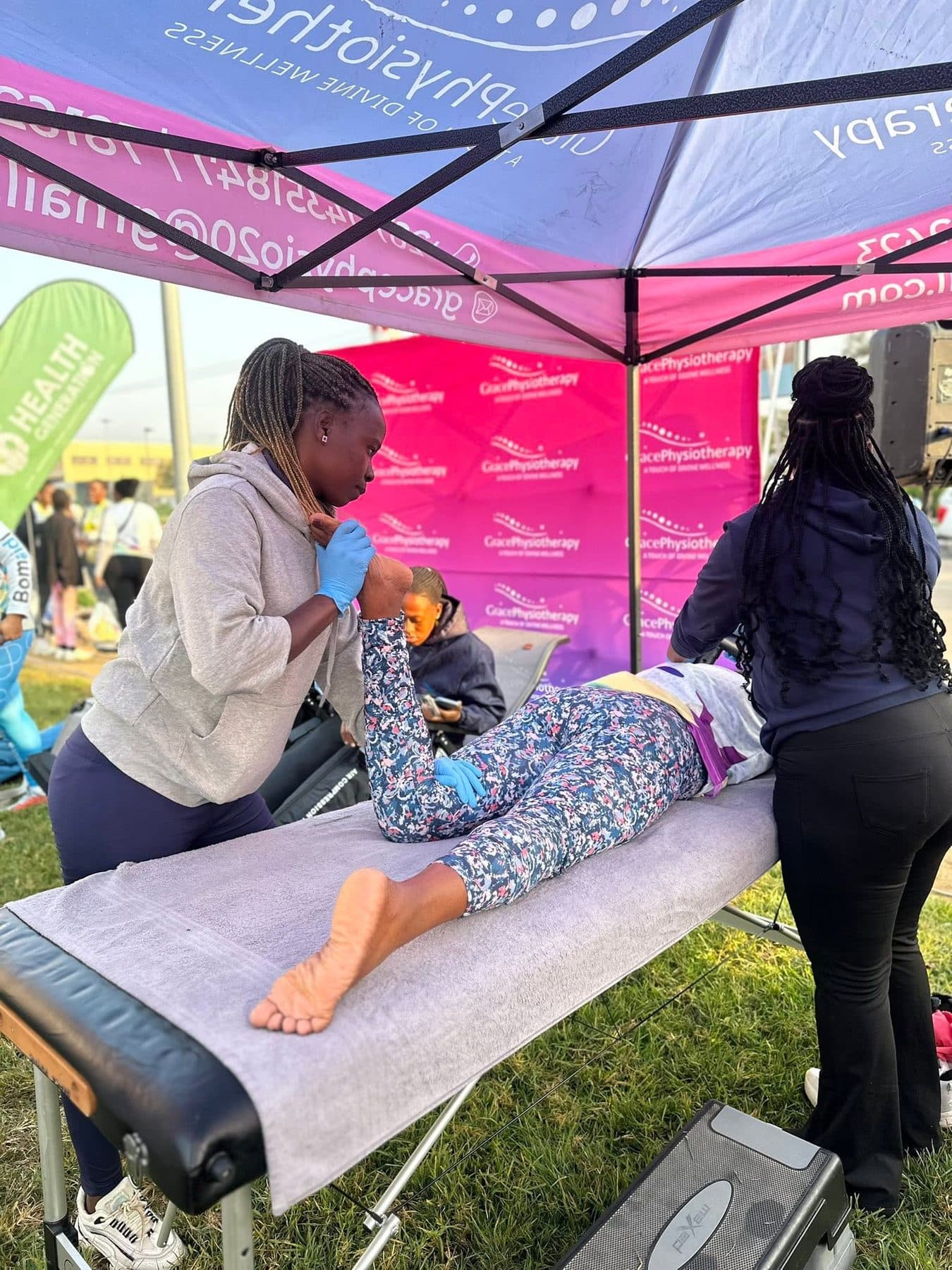 A Grace Physiotherapy therapist treating a young child lying on a treatment table at a community event.