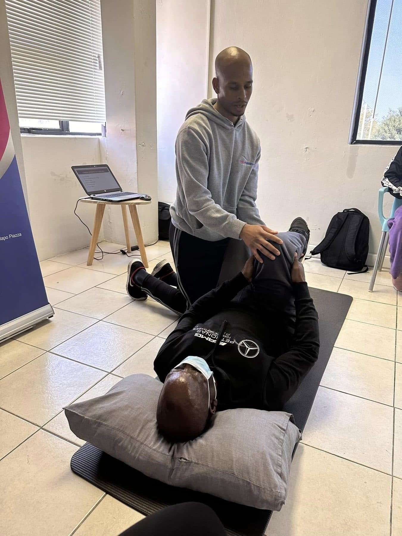 A Grace Physiotherapy therapist mobilising a patient's leg during a treatment session on the clinic floor.